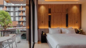 A modern hotel room with a large bed, a balcony with seating, and a view of the building's exterior. - RICHMANN RESORT HOTEL HATYAI (Hat Yai)