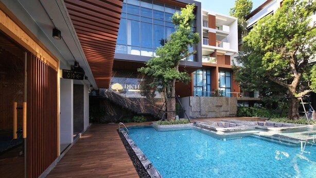 A modern building with a swimming pool, wooden deck, and a sign indicating a toilet.