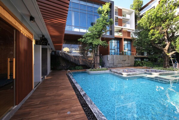 A modern building with a swimming pool, wooden deck, and a sign indicating a toilet. - RICHMANN RESORT HOTEL HATYAI (Hat Yai)