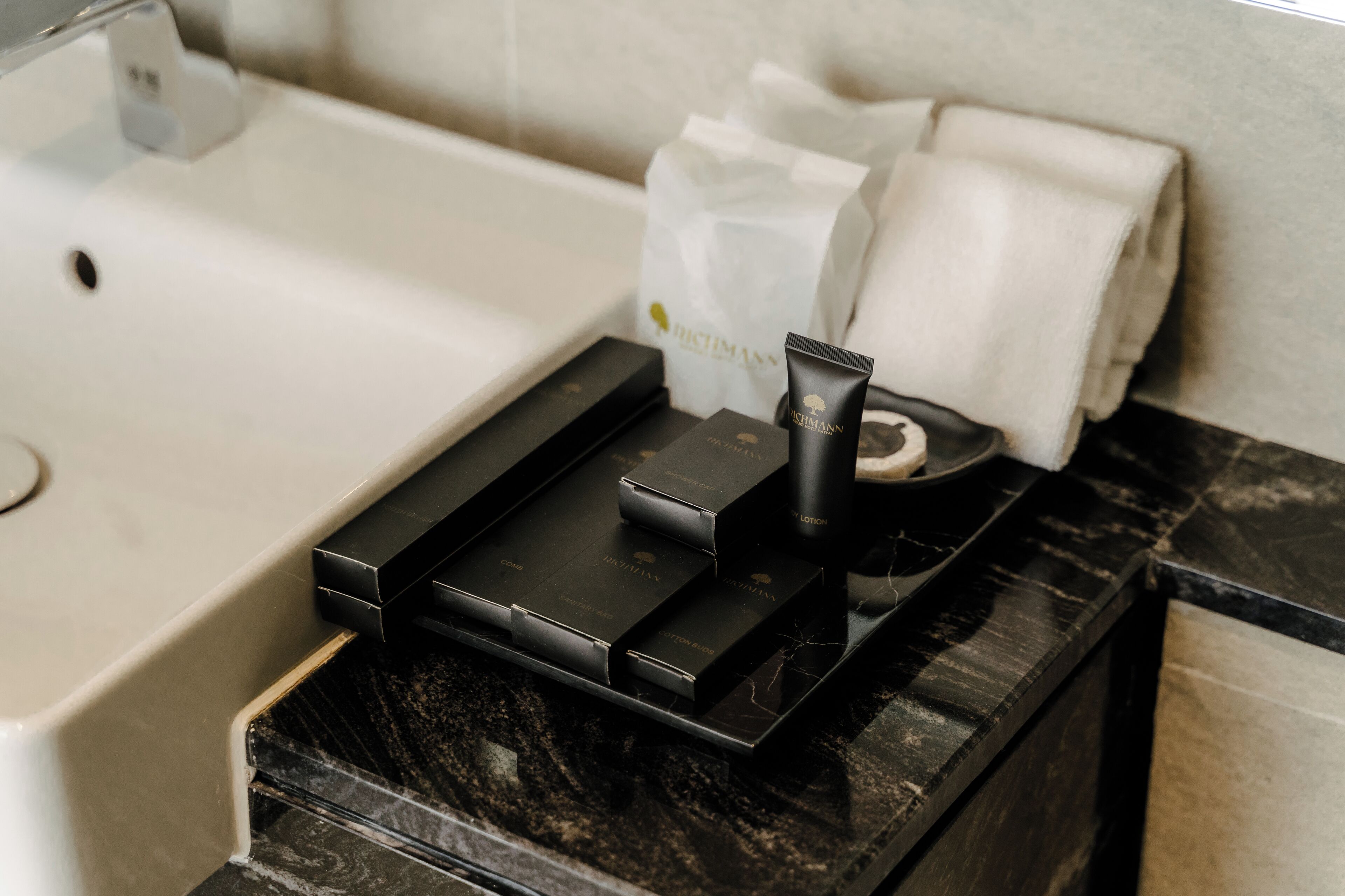 A bathroom vanity with a black marble countertop, a sink, and a tissue box.
