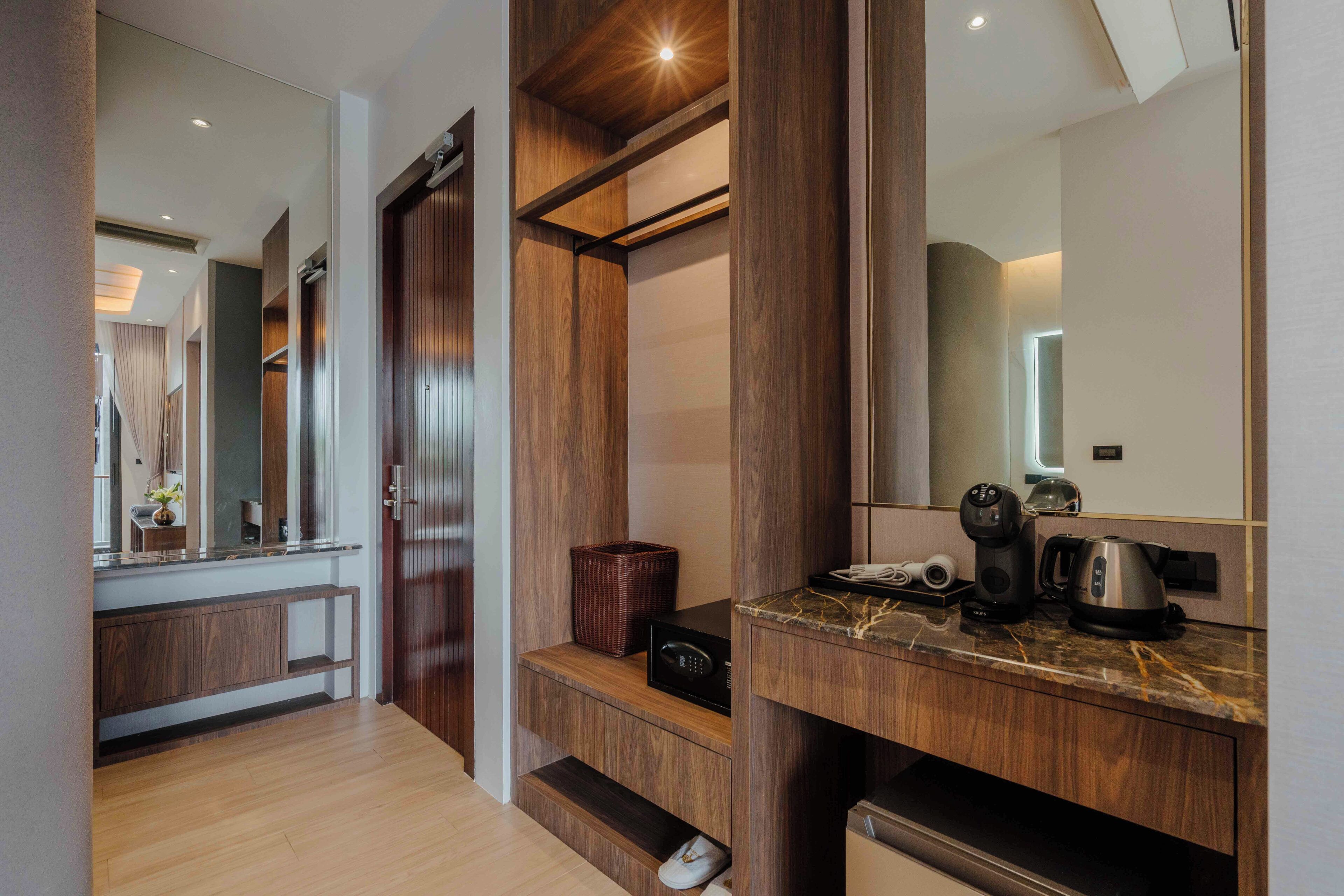 A modern bathroom with a wooden vanity, a large mirror, and a built-in coffee maker.