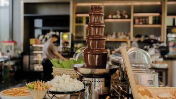 Montaje de bufé con una fuente de chocolate, diversos alimentos y una barra de servicio.