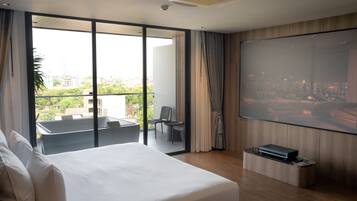 Quarto de hotel moderno com uma cama grande, varanda com vista para a cidade, televisão de tela plana e um pequeno espaço de estar.