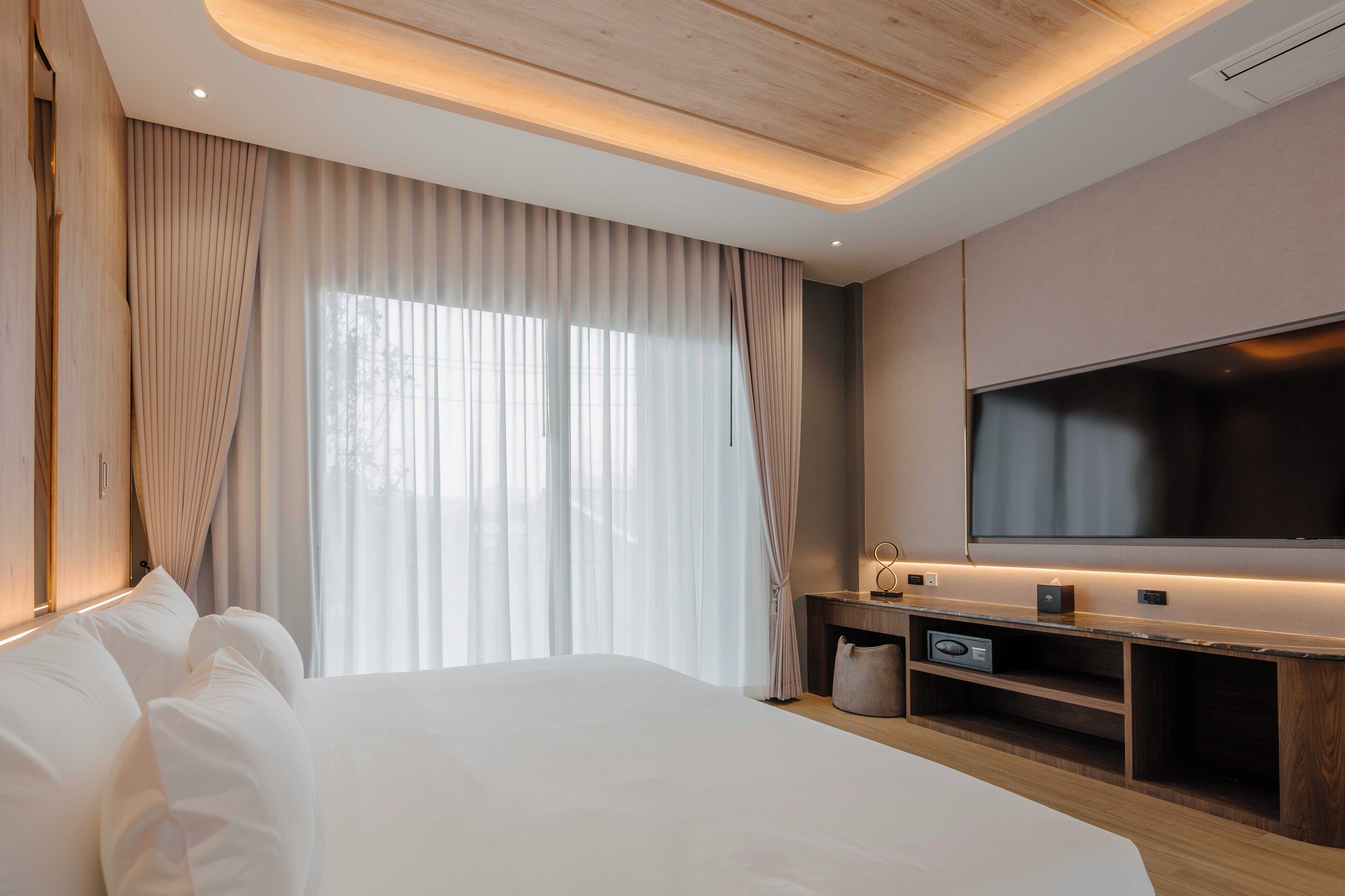 Una habitación de hotel moderna con una cama grande, un televisor de pantalla plana y un mueble de entretenimiento de madera.