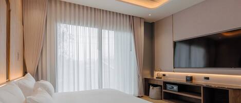 Una habitación de hotel moderna con una cama grande, un televisor de pantalla plana y un mueble de entretenimiento de madera.