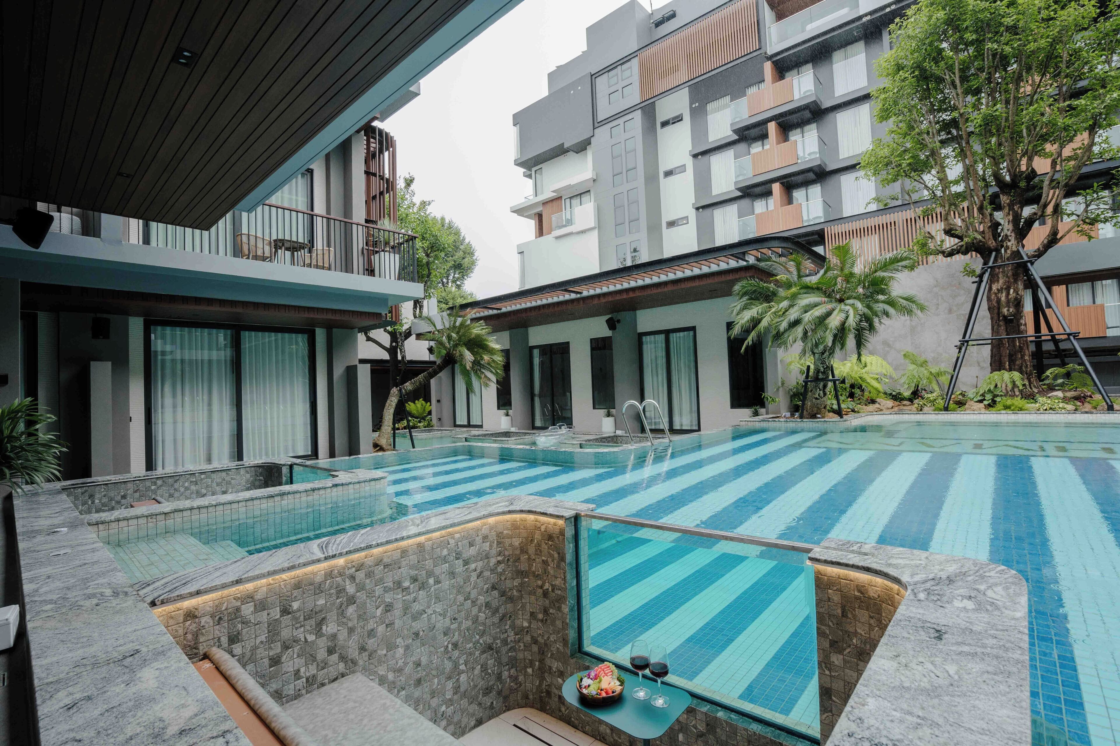 Un hotel moderno con piscina, mobiliario exterior y vistas de los edificios circundantes.