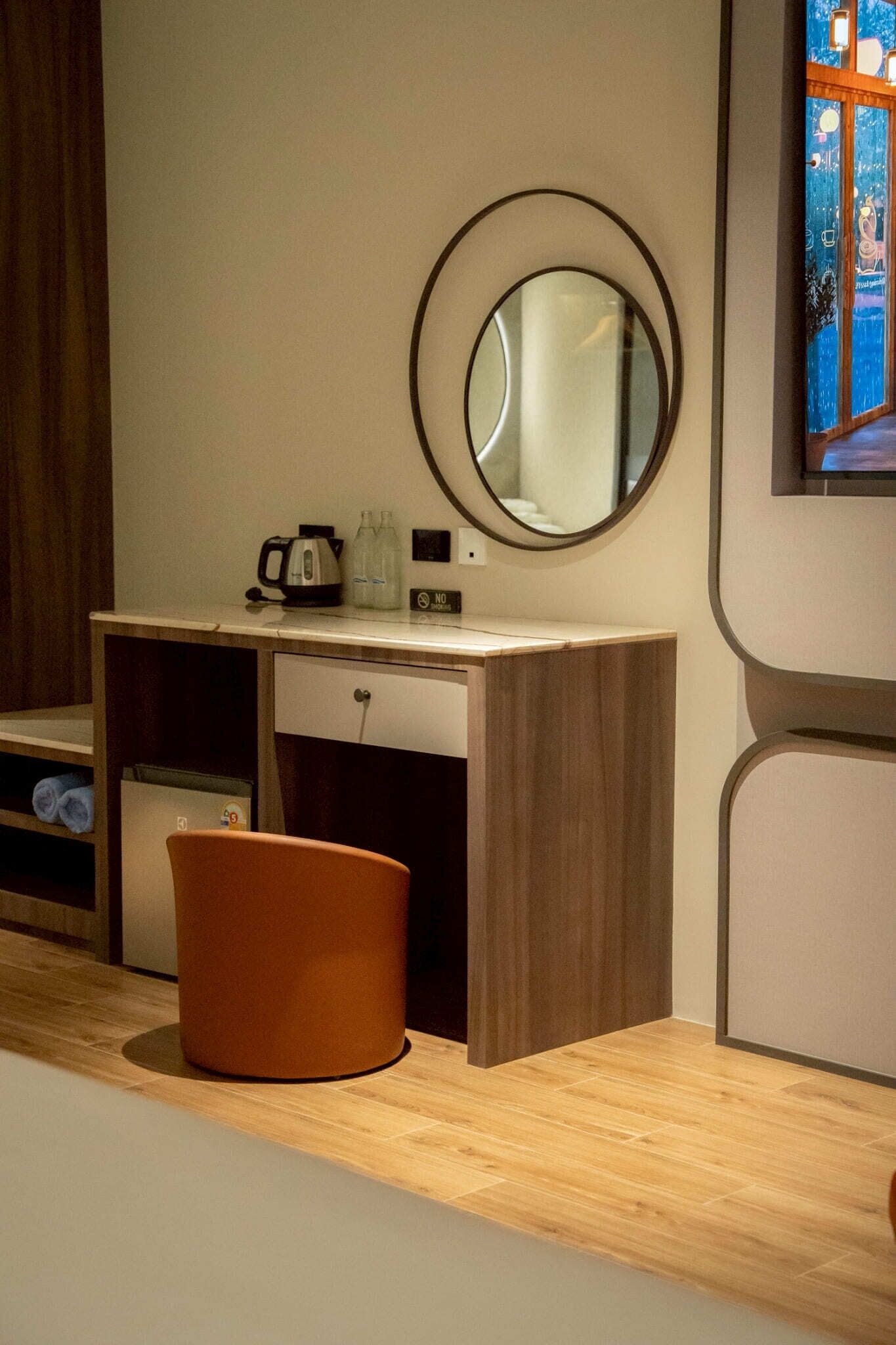 A modern bathroom with a wooden vanity, a round mirror, a sink, and a toilet.