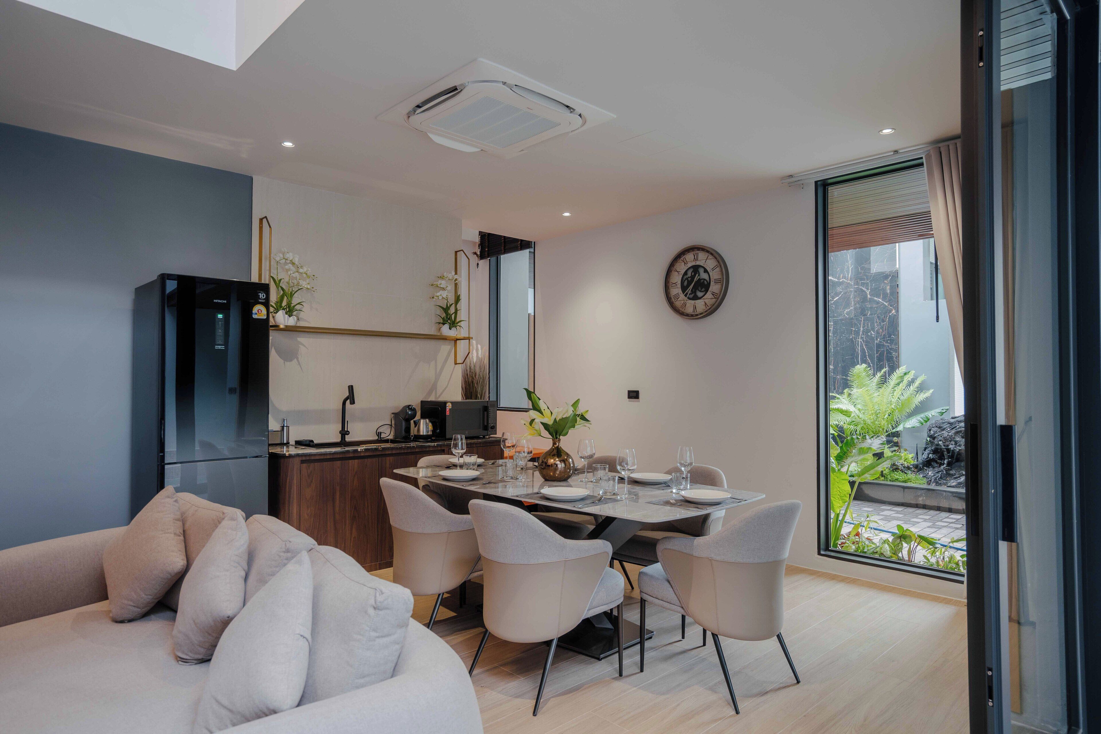 Un espace repas moderne avec une grande table, des chaises et une cuisine en arrière-plan.