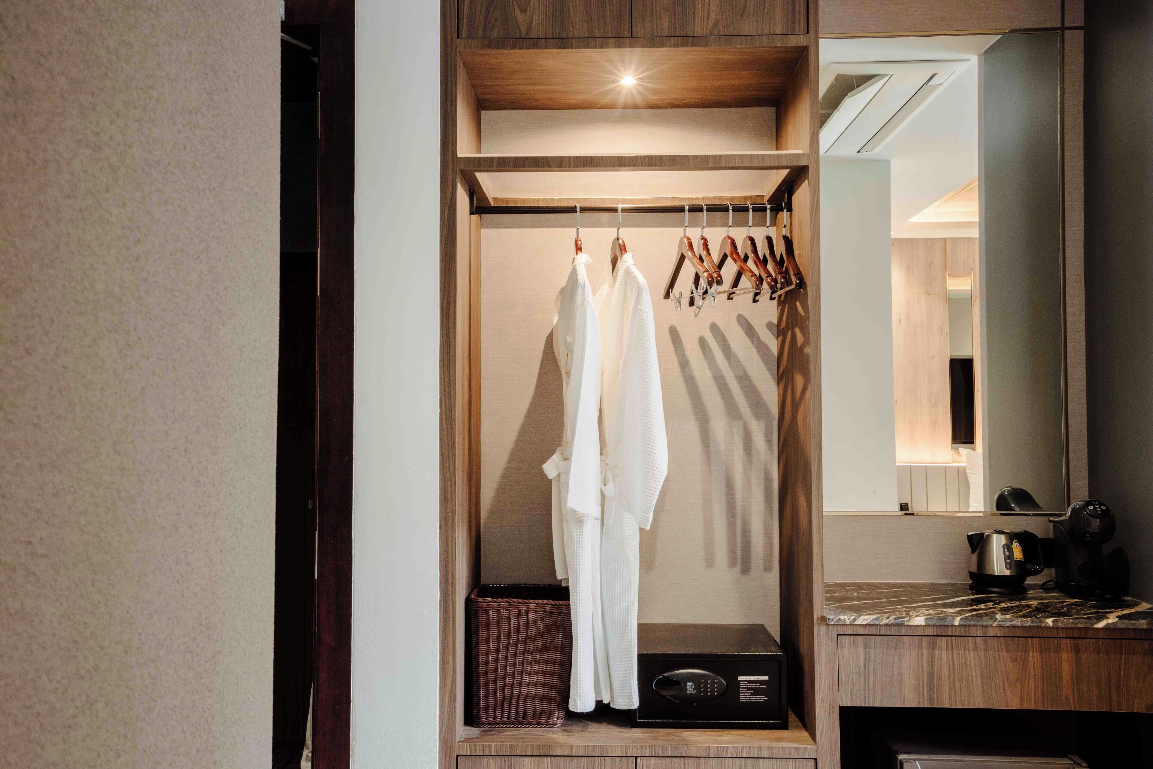 A walk-in closet with wooden shelving, a hanging rack, and a microwave.