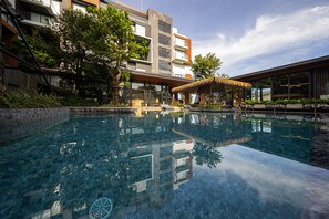 A modern hotel with a clear pool, outdoor seating, and lush greenery. - RICHMANN RESORT HOTEL HATYAI (Hat Yai)