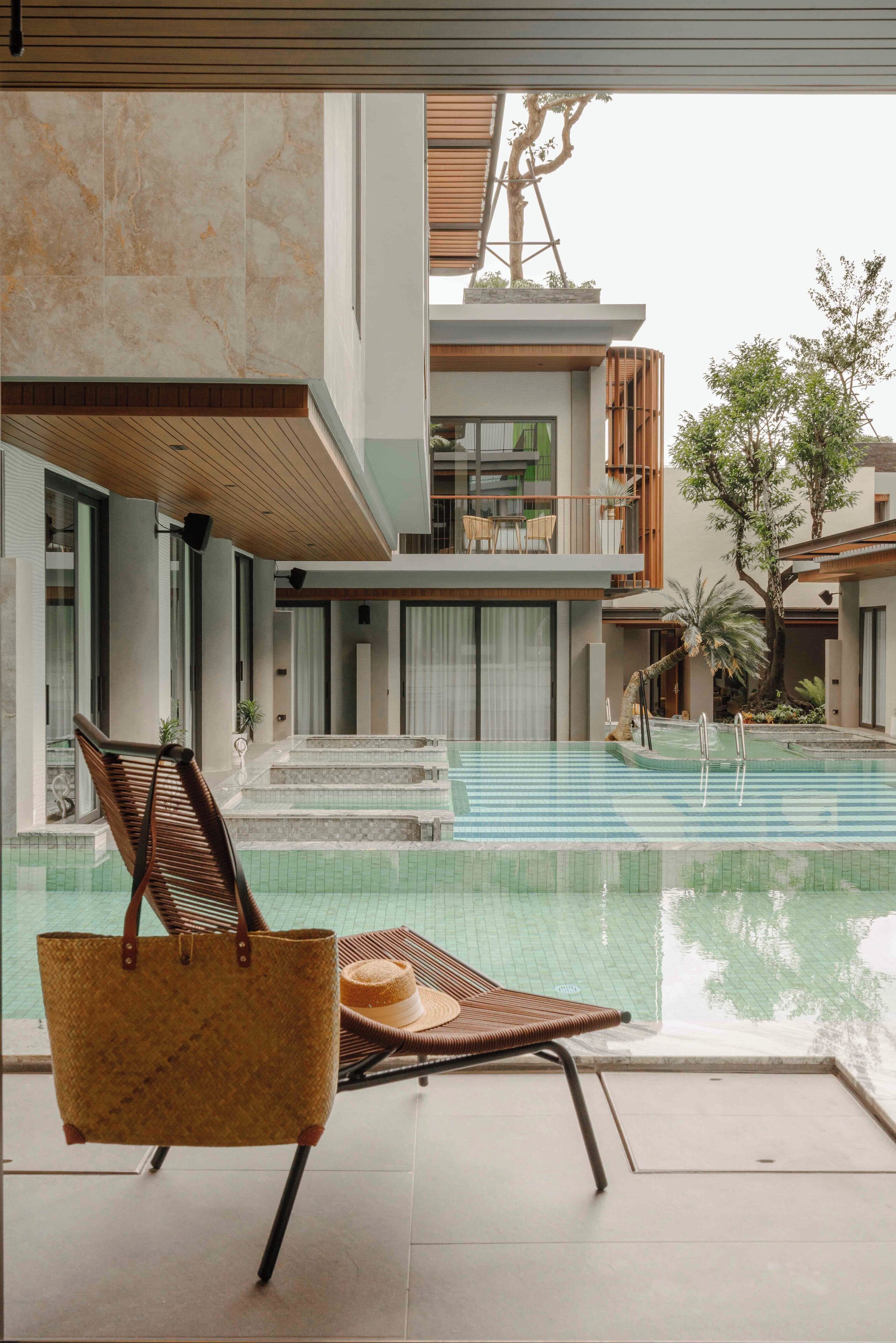 Uma área de piscina moderna com uma espreguiçadeira e uma cesta de vime.