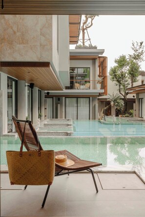 A modern pool area with a lounge chair and a wicker basket.