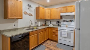 Une cuisine avec des meubles de rangement en bois, un lave-vaisselle, une cuisinière et un réfrigérateur.