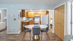 Une cuisine moderne avec des meubles en bois, un îlot central et un coin repas comprenant une table ronde et des chaises.