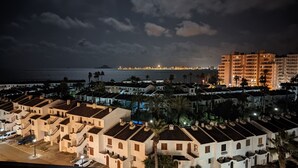 Uma área residencial costeira com edifícios brancos, alguns com telhados de telhas vermelhas, e alguns edifícios mais altos ao fundo.