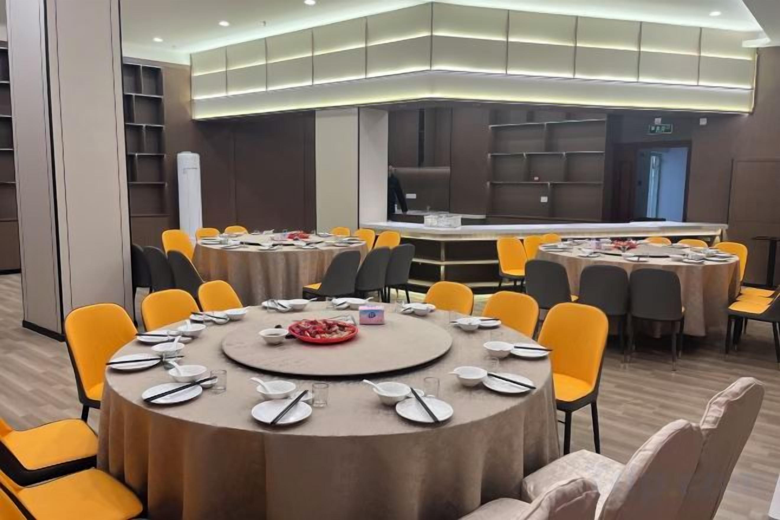 Un salón de conferencias con mesas redondas, sillas y una zona de buffet.