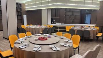 Un salón de conferencias con mesas redondas, sillas y una zona de buffet.
