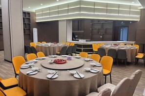 A conference room with round tables, chairs, and a buffet area.