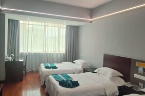 A hotel room with two beds, a desk, a chair, and a window with curtains.