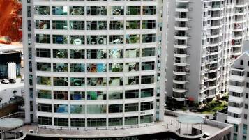 Um hotel moderno com fachada de vidro, várias varandas e um terraço no telhado.