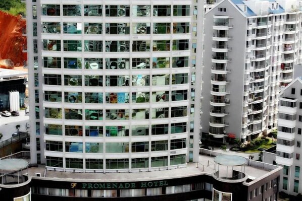 A modern hotel with a glass facade, multiple balconies, and a rooftop terrace.