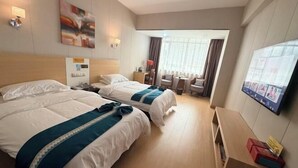 Une chambre d’hôtel avec deux lits, un bureau, une chaise, une télévision et une fenêtre avec des rideaux.