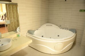 A modern bathroom with a large freestanding bathtub, a round sink, and a mirror. - Promenade Hotel (Pingnan)