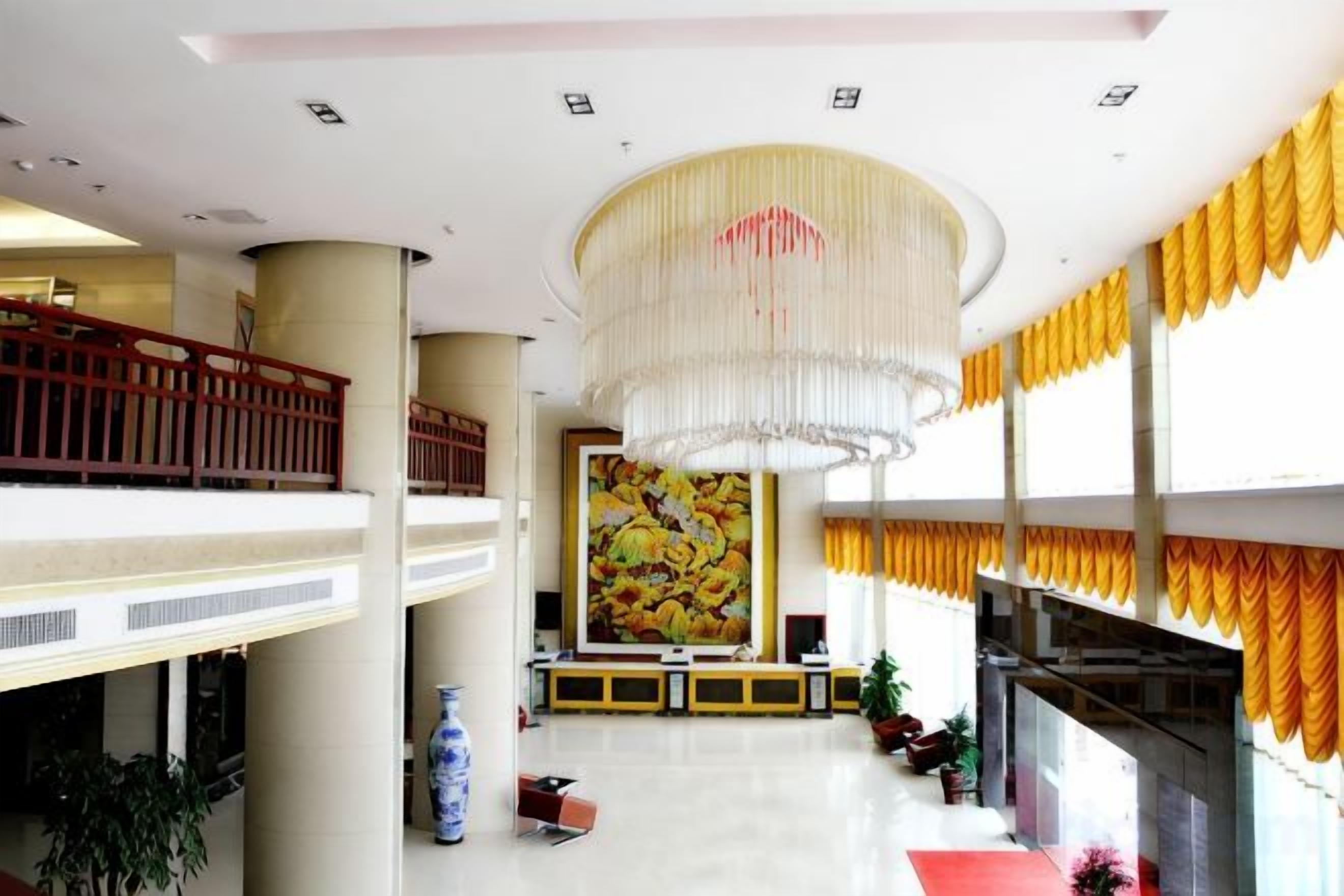 A spacious lobby with a high ceiling, a large chandelier, and a prominent fruit-themed painting.