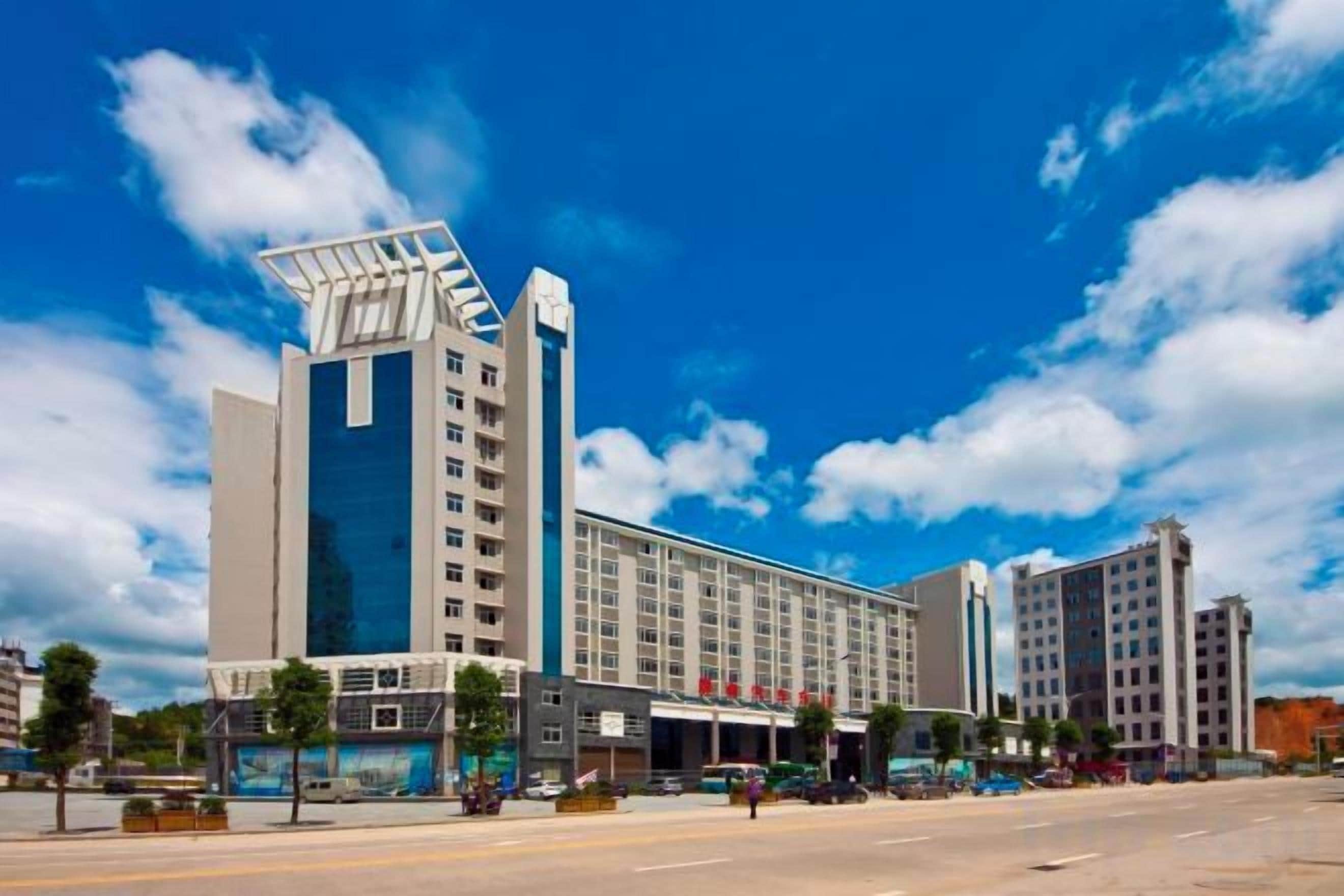 Een meerlaags hotel met een modern ontwerp, met een opvallende glazen gevel en een plat dak.