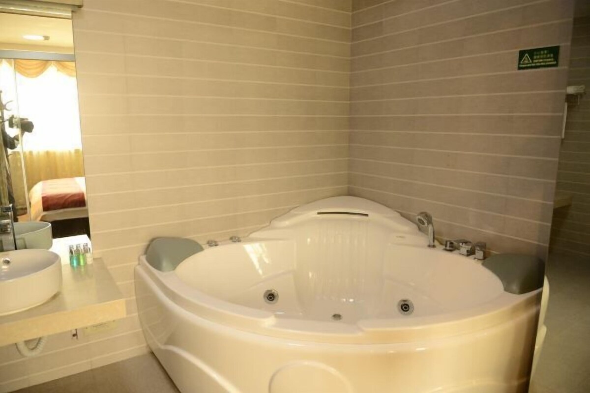 A bathroom with a large bathtub, a sink, and a mirror.