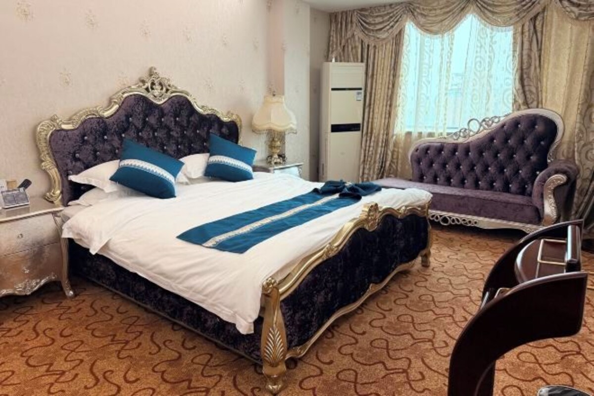 Quarto com uma cama grande, uma cadeira, uma mesa de cabeceira e um guarda-roupa.