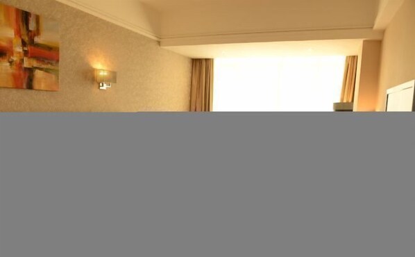 A hotel room with a large window, a wall-mounted light fixture, and a partial view of a painting. - Promenade Hotel (Pingnan)