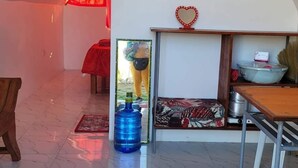 A room with a tiled floor, a wooden table, a chair, a red heart-shaped decoration, and a mirror on the wall. - Live N Love (Pasuquin)