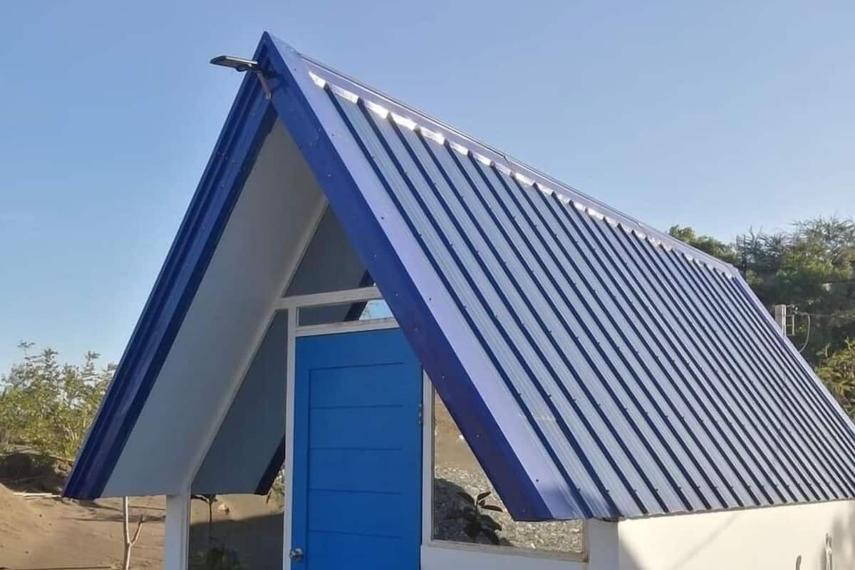 Pieni, yhden kerroksen rakennus, jossa on sininen ovi ja kalteva metallikatto.