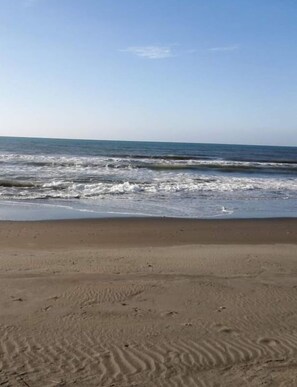 A sandy beach with visible footprints and waves approaching the shore. - Live N Love (Pasuquin)
