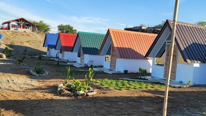 A row of small, single-story buildings with sloped roofs, surrounded by a landscaped garden with sparse vegetation. - Live N Love (Pasuquin)