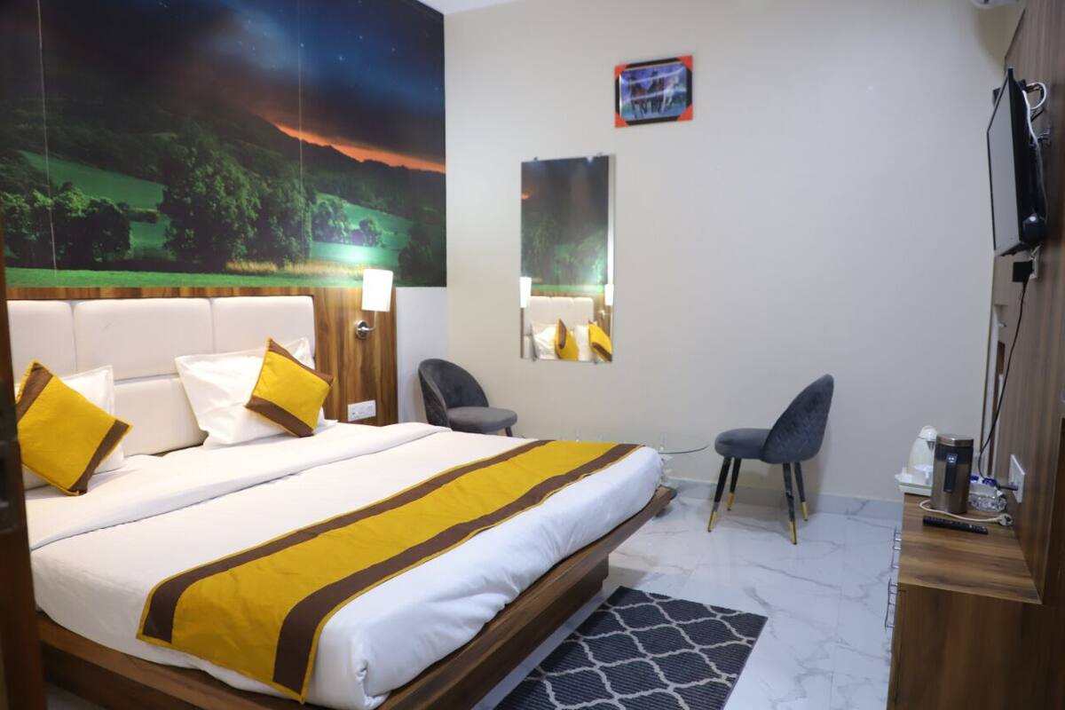 Ein Hotelzimmer mit Bett, Schreibtisch, Stuhl, Spiegel und Fernseher.