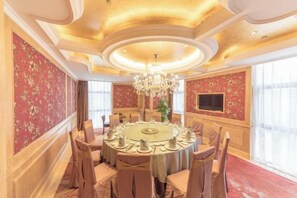 A formal dining room with a round table, chairs, and a chandelier.