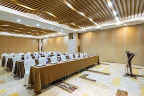 Un salón de conferencias con una mesa larga, sillas y un atril.