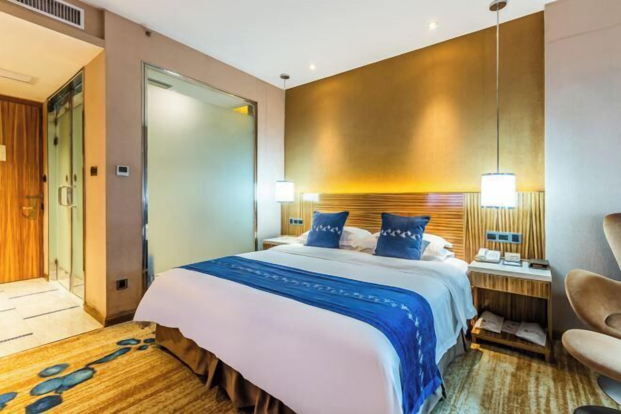 Ett hotellrum med en säng, sängbord, en stol och en dörr.