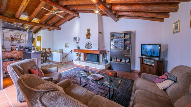 Una sala de estar acogedora con vigas de madera, chimenea, televisor y asientos cómodos.