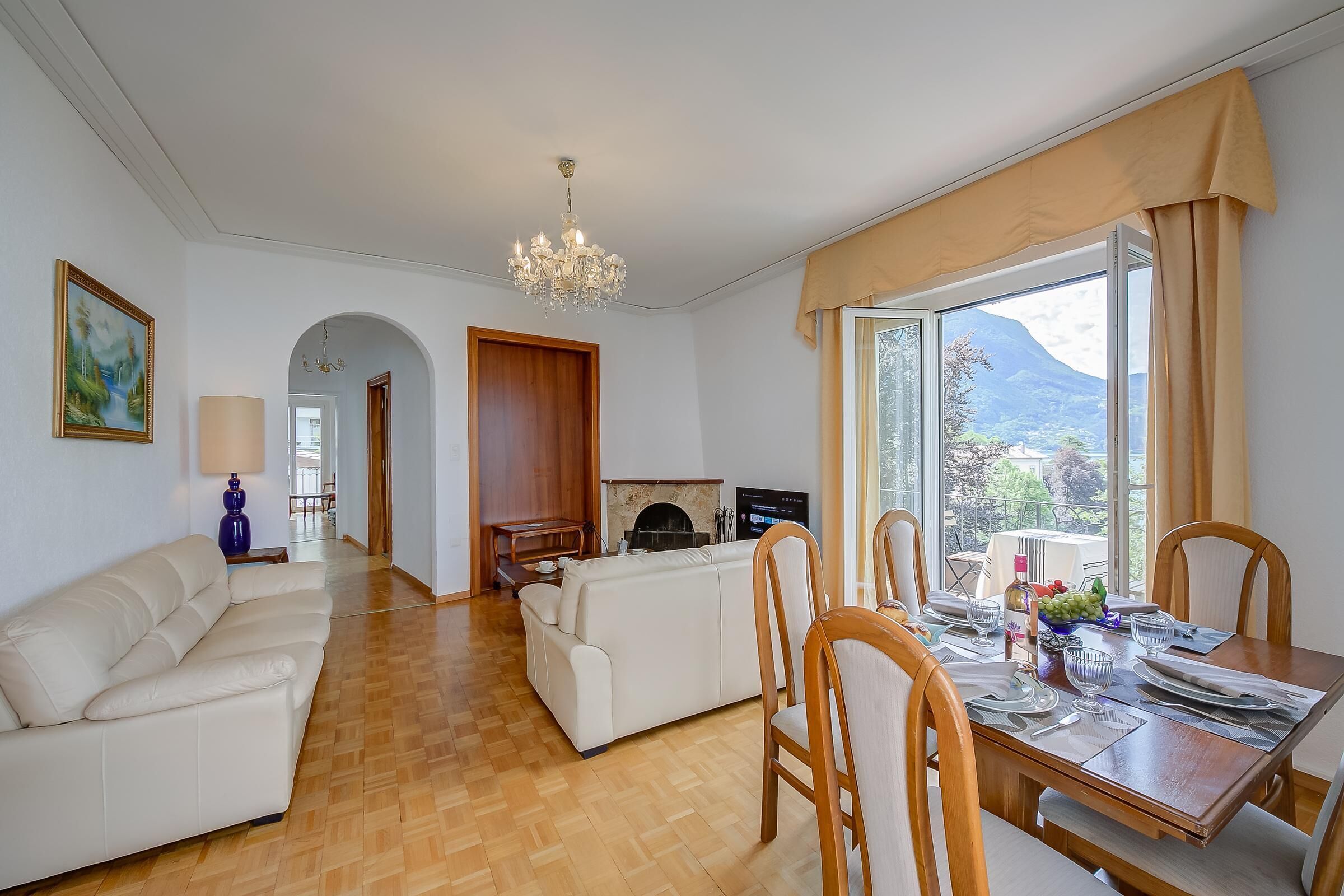 Een woonkamer met een bank, een eettafel gedekt voor twee personen, en een open haard.