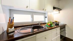 Cucina con lavello doppio, piano di lavoro in legno, pensili bianchi e finestra sopra il lavello.
