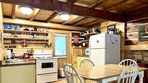 Una cocina acogedora con vigas de madera, un refrigerador blanco, una estufa y una mesa de comedor con sillas.