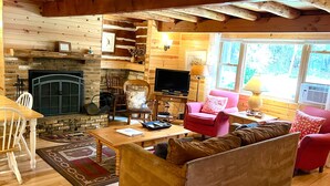 Un interior acogedor de cabaña con chimenea de piedra, muebles de madera y un televisor.
