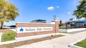 A sign for Indiana State University with a clear sky and buildings in the background.