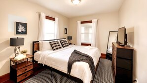 A neatly arranged bedroom with a bed, bedside tables, a dresser, and a television.