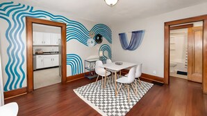 A modern kitchen with white cabinets, a dining area with a white table and chairs, and a patterned rug.