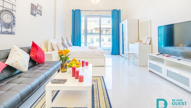 A modern living room with a sofa, coffee table, and TV. - MK Residence By Be Our Guest (Dubai)