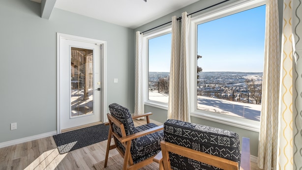 A room with a large window, a door, and two patterned chairs. - 1 bedroom and kitchen place with a valley scenery view & free parking (CALGARY)